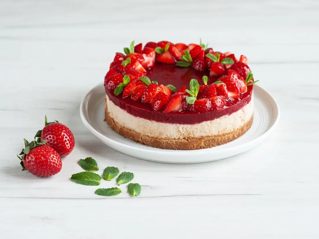 Ganze Cheesecake-Torte mit frischen Erdbeeren auf einem weißen Teller