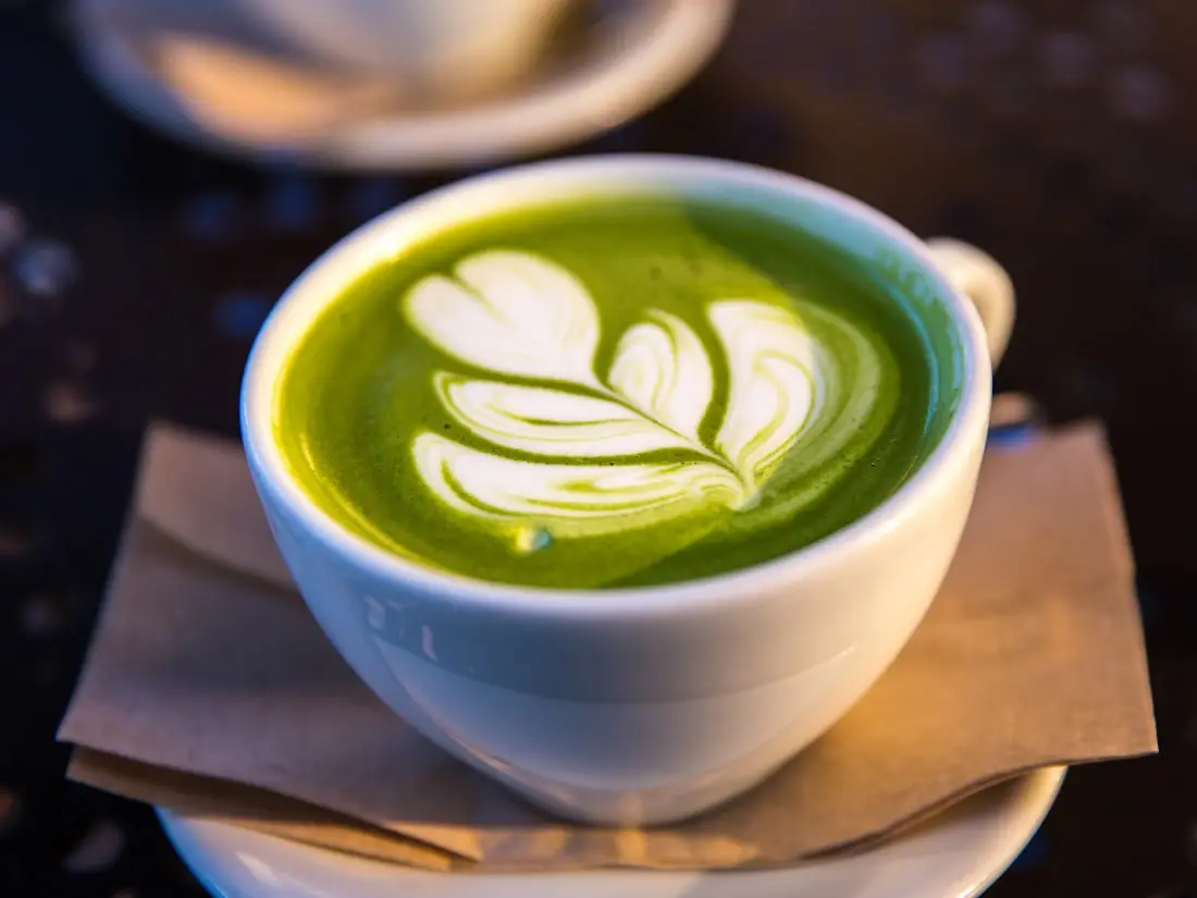 Matcha Latte mit Milchschaum-Muster in einer hellen Keramiktasse